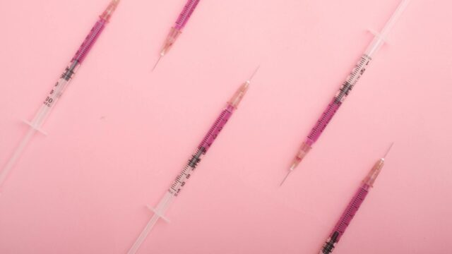 set of medical syringes filled with medication on pink desk